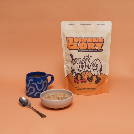 Bag of 'Morning Glory' oats with a bowl, cup, and spoon on an orange background