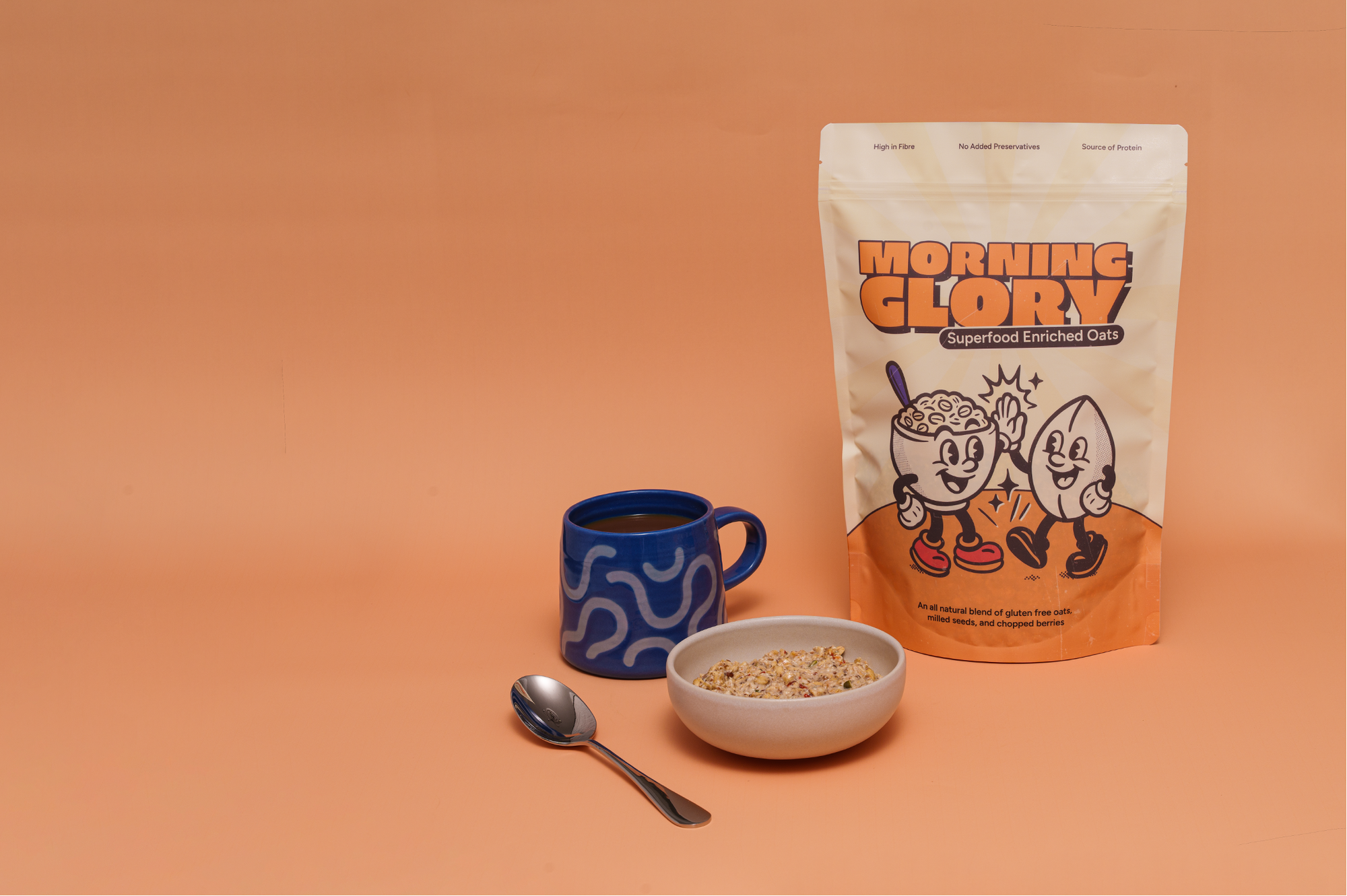 Morning Glory Superfood Enriched Oats package with a cup, bowl of overnight oats and spoon on an orange background